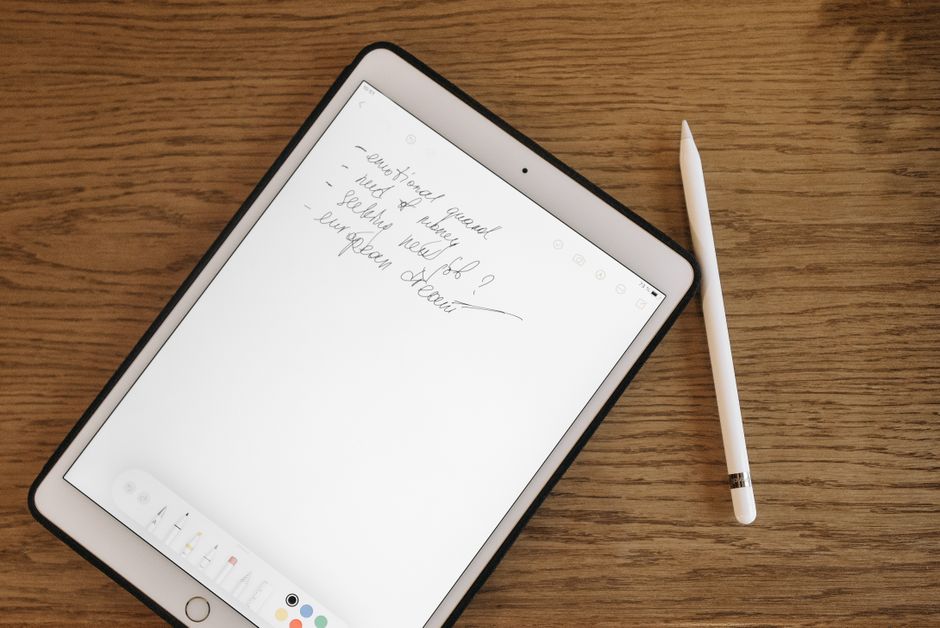 Tablet z odręcznymi notatkami i rysikiem leżący na drewnianym stole.