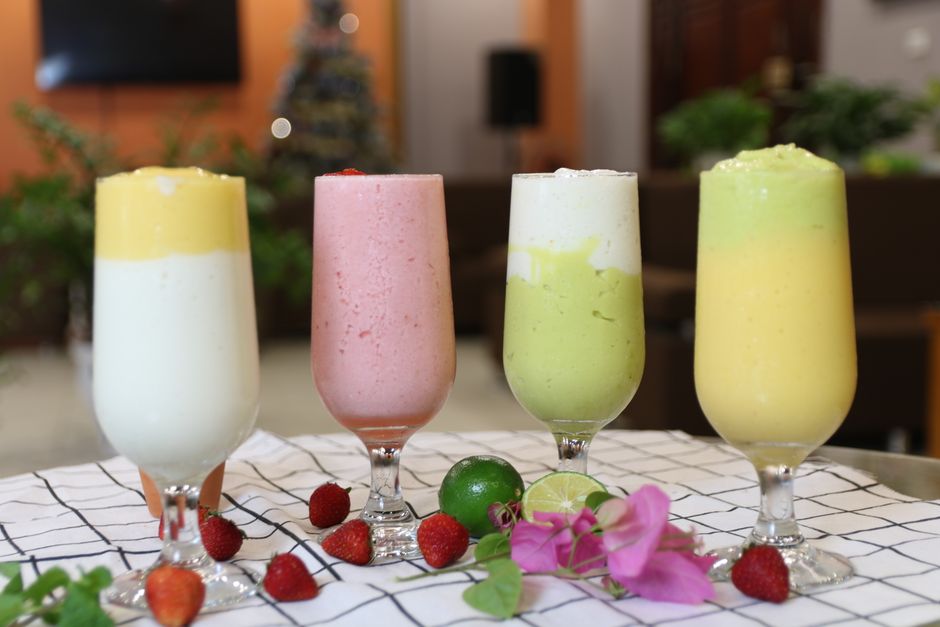 Cztery szklanki z kolorowymi koktajlami owocowymi na obrusie w kratę
